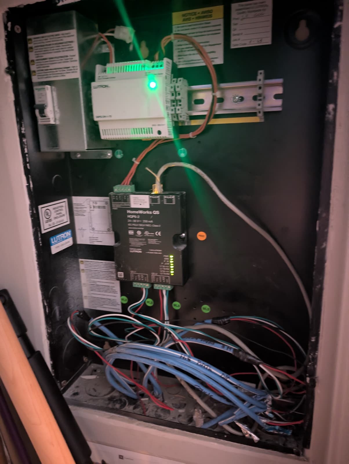 A Lutron HomeWorks QS processor in a dark panel enclosure with loose low-voltage wiring