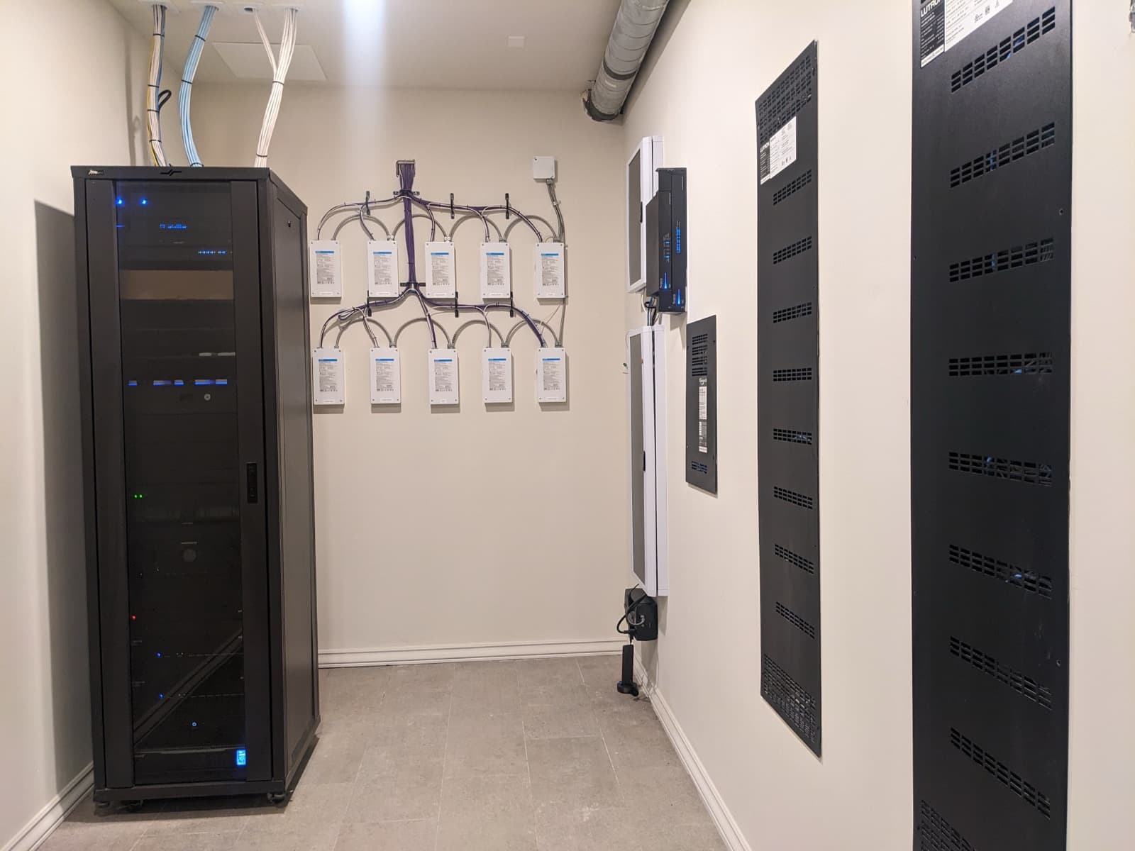 Finished equipment room with lighting panels, rack, and organized wall-mounted equipment