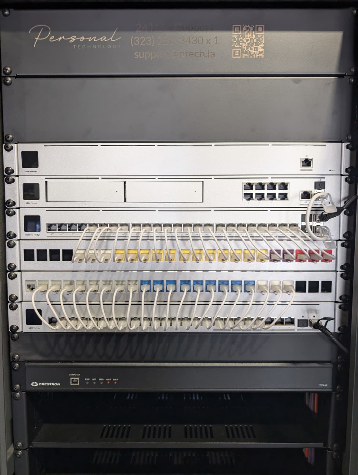 A finished network rack with a Personal Technology support panel, UniFi gateway and switches, and color-coded patch panels