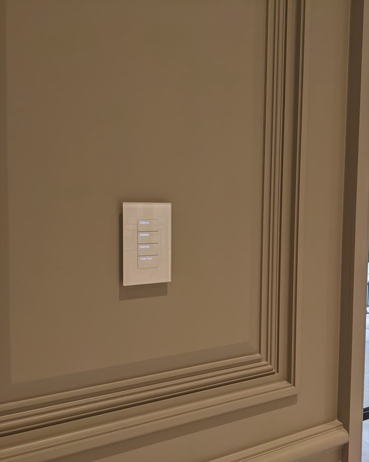 A glass Palladiom keypad with backlit engraved buttons on a paneled wall